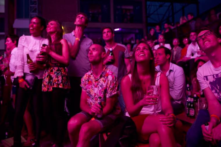 Partygoers watch the opening ceremonies on a massive LCD screen at Fringe 2012.