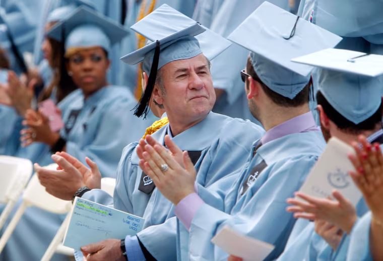 Columbia University janitor Gac Filipaj, center, looks on during the Columbia University School of General Studies graduation ceremony, May 13, 2012, in New York. Filipaj, an ethnic Albanian who left his native Montenegro 20 years ago to escape war, is graduating with honors after 12 years of balancing studies and his full-time job.