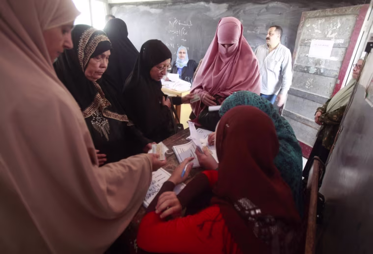 Women show their ID before casting their votes at a polling station in Al-Sharqya, northeast of Cairo Wednesday.