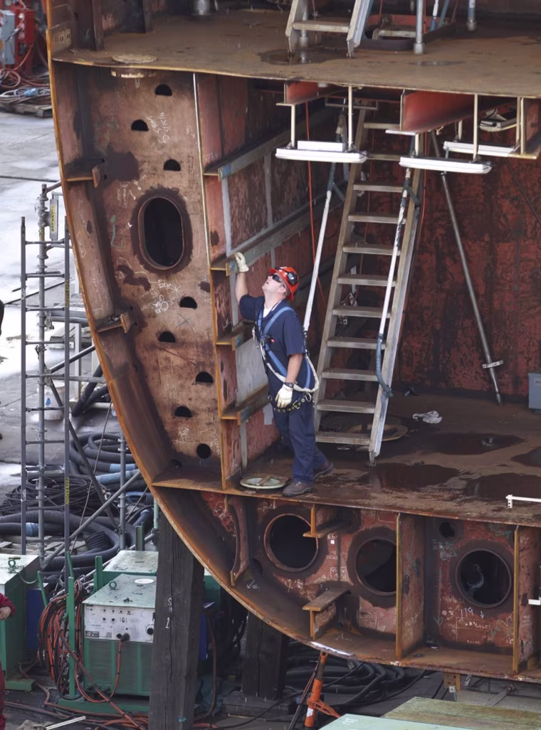 A shipyard worker stands in the lower hull as the lower bow section of the nuclear powered aircraft carrier Gerald R. Ford is lowered into position at Newport News Shipbuilding in Newport News, Va., Thursday.