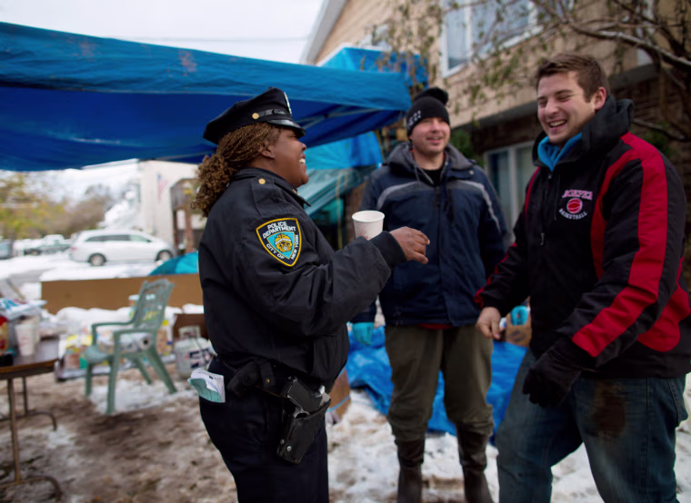 NYPD Officer Cornelia Samuels compliments volunteers Robert Servis and David Lauer, right, on the roasted red pepper soup they served from their outdoor kitchen on the corner of Brighton Street and Billup Avenue in Staten Island on Thursday morning.