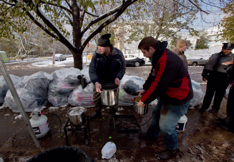 Volunteers Robert Servis and David Lauer, right, prepare soup at their outdoor kitchen in Staten Island on Thursday morning.