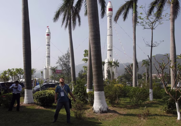 A visitor watches a flight demonstration in front of Long March CZ-3B (right) and CZ-2E rockets on the first day of the China International Aviation & Aerospace Exhibition, November 13, 2012.