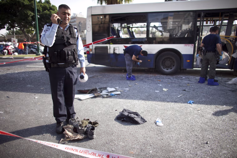 An Israeli policeman stands above shoes and clothes from a victim at the scene of an explosion on a bus in central Tel Aviv, Israel, Nov. 21.