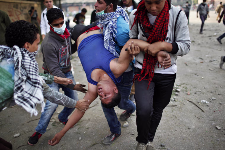 Anti-Morsi protesters carry a wounded man away from tear gas during clashes with riot police at Tahrir square in Cairo, Nov. 27.