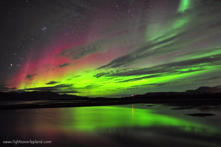 The auroral display takes on different hues over Sweden's Abisko National Park. The color variations are due to the differences in the composition of the atmosphere at different altitudes. The greenish glow dominates, but the aurora can turn reddish at higher altitudes, as seen here. Check out the Causes of Color website to learn more about auroral colors.