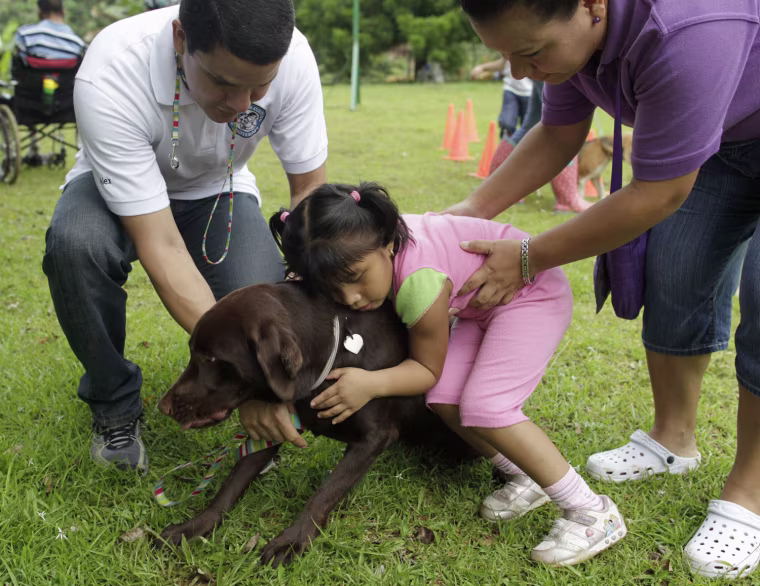 Anais Nickol, with cerebral palsy, hugs Hershey, a therapeutically trained dog, during a therapy session.