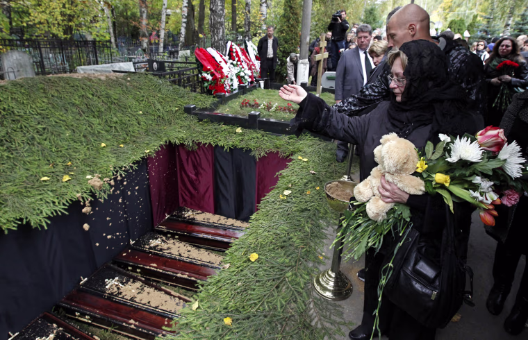 Orphanage teachers and schoolmates throw handfuls of soil into a common grave during the funeral for car accident victims in Moscow Sept. 26.