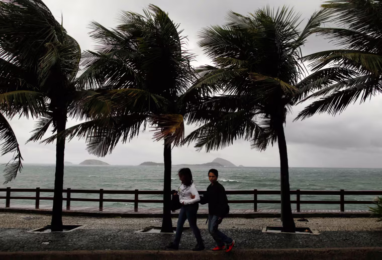 People walk along the coast on a cold day at Leblon beach in Rio de Janeiro on Sept. 26. According to local media, temperatures have fallen down to about 16 degrees Celcius (60 degrees Fahrenheit) and winds could reach speeds of almost 76 km (47 miles) per hour.