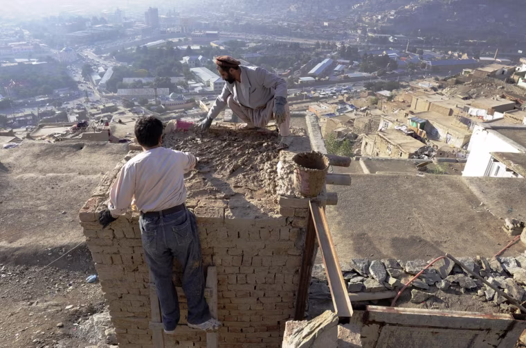 Saber, a resident of the hillside neighborhood of Jamal Mina applies a layer of concrete to a room he was adding to his home high above downtown Kabul on Sept. 27.