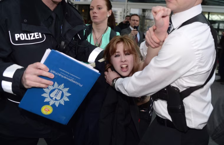A demonstrator is held by security staff.