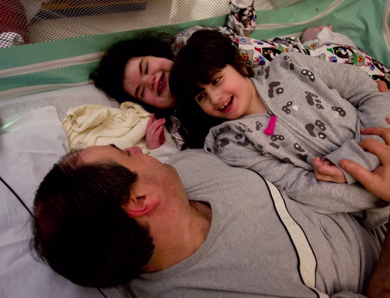There's no cure for Hayley and Bari Mogul's rare genetic conditions. But physical therapy helps, and so does roughhousing with their dad.