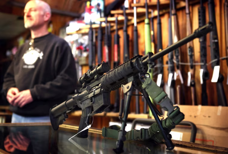 An AR-15 style rifle sits on the counter by Craig Marshall as he assists a customer at Freddie Bear Sports sporting goods store on December 17, 2012, in Tinley Park, Ill.