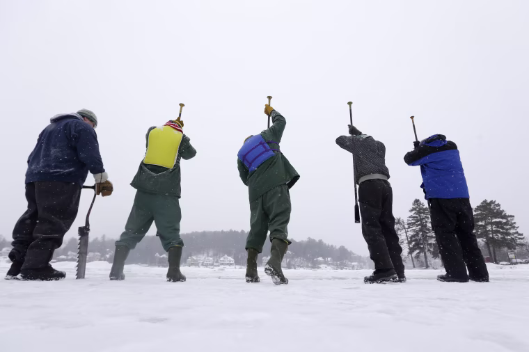 Inmates from the Moriah Shock Incarceration Correctional Facility, wearing green, work with volunteers breaking off ice blocks from Lake Flower that will be used to construct the Saranac Lake Winter Carnival ice palace on Jan. 28, in Saranac Lake, N.Y.