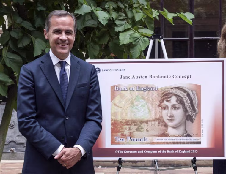 Bank of England Governor Mark Carney poses next to a new British ten pound Sterling banknote bearing the likeness of author Jane Austen in a picture r...