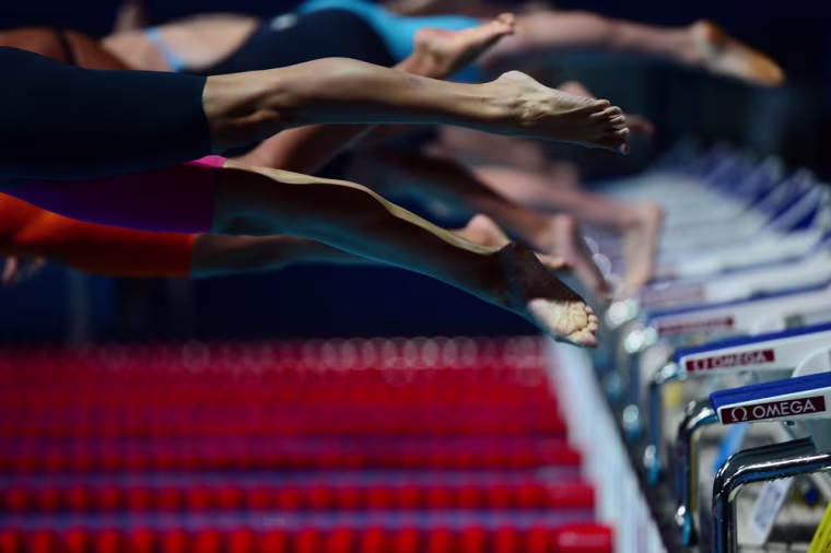 Participants jump as they compete in the heats of the Women's 200m freestyle swimming event.