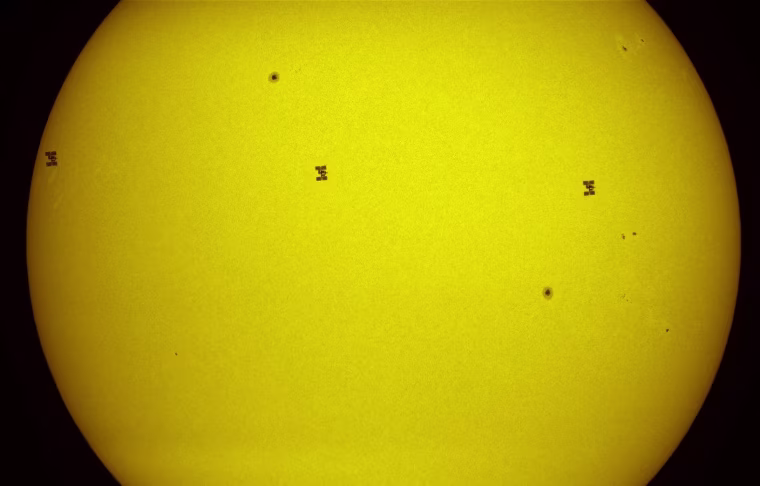 A three-image composite tracks the International Space Station and the shuttle Atlantis as they move across the sun's disk on July 15.