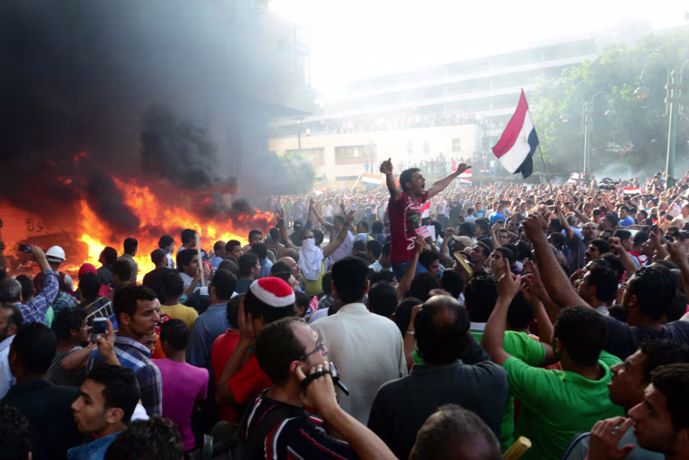 Opponents of Egypt's Islamist President Mohammed Morsi chant slogans as fire rages at the Muslim Brotherhood headquarters in Alexandria, on June 28, 2013.