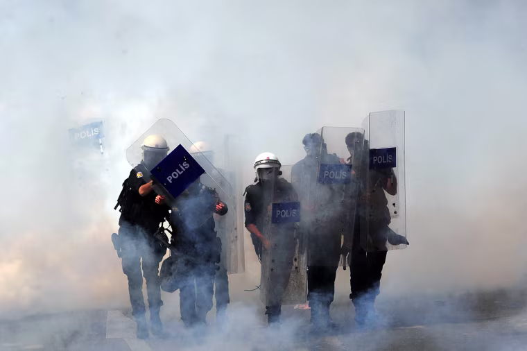 Masked policemen take cover behind shields during clashes at a May Day demonstration on May 1, in Istanbul.