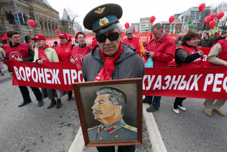 An elderly Russian Stalinist stands in front of a column of demonstrators with a portrait of Stalin during a traditional May Day communist demonstration, in Moscow, Russia. People from around the world are marking May 1 (May Day) as International Labour Day.