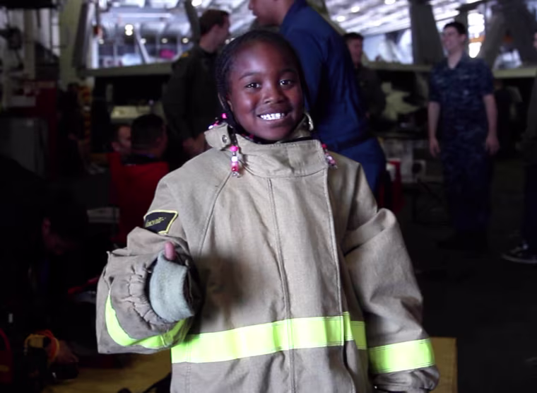 Aaniya Dorrah tries on a fireman's suit on the John C. Stennis.
