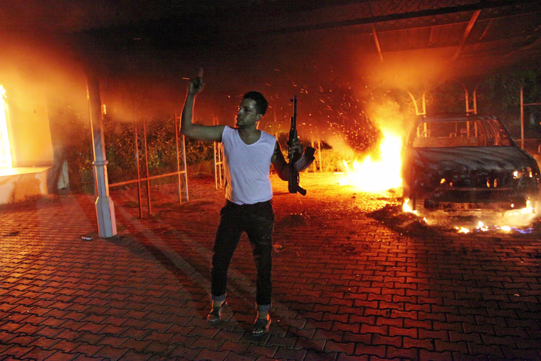 TOPSHOTS An armed man waves his rifle as buildings and cars are engulfed in flames after being set on fire inside the US consulate compound in Benghazi late on September 11, 2012. An armed mob protesting over a film they said offended Islam, attacked the US consulate in Benghazi and set fire to the building, killing one American, witnesses and officials said. AFP PHOTOSTR/AFP/GettyImages