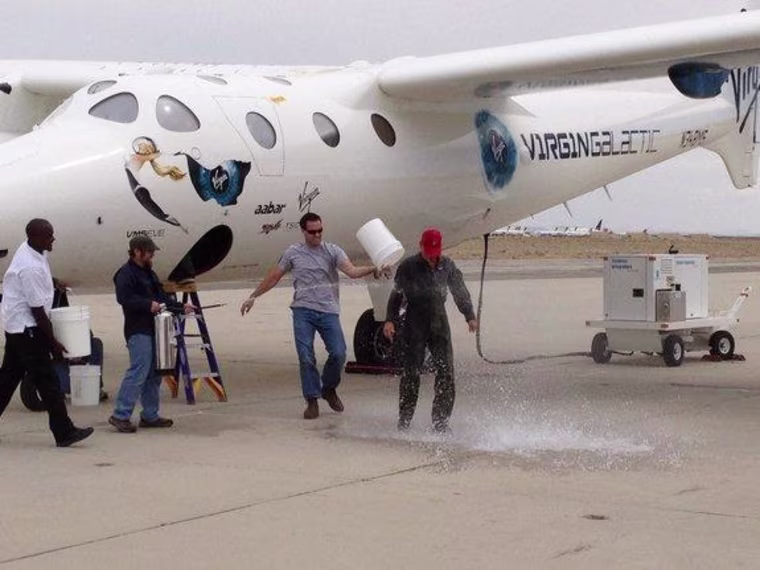 New Virgin Galactic pilot C.J. Sturckow, a four-time space shuttle astronaut, gets a traditional dousing after flying the company's WhiteKnightTwo mot...