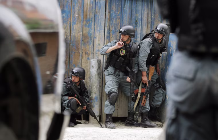 Afghan police take cover during a gubattle following a suicide attack in Kabul, Afghanistan, on May 24, 2013. A suicide bomber struck in the heart of the Afghan capital on Friday, sending a plume of smoke billowing over Kabul and setting up a gunbattle in the second major attack in the city in little over a week, police said.