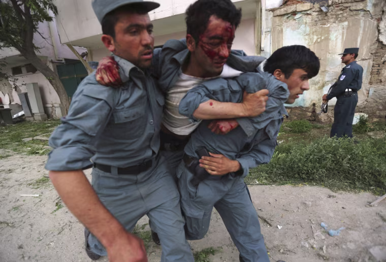 A wounded Afghan policeman is being carried away from the site of an explosion in Kabul on May 24, 2013.