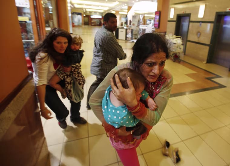 Women carrying children run for safety as armed police hunt gunmen who went on a shooting spree in Westgate shopping centre in Nairobi September 21, 2013.
