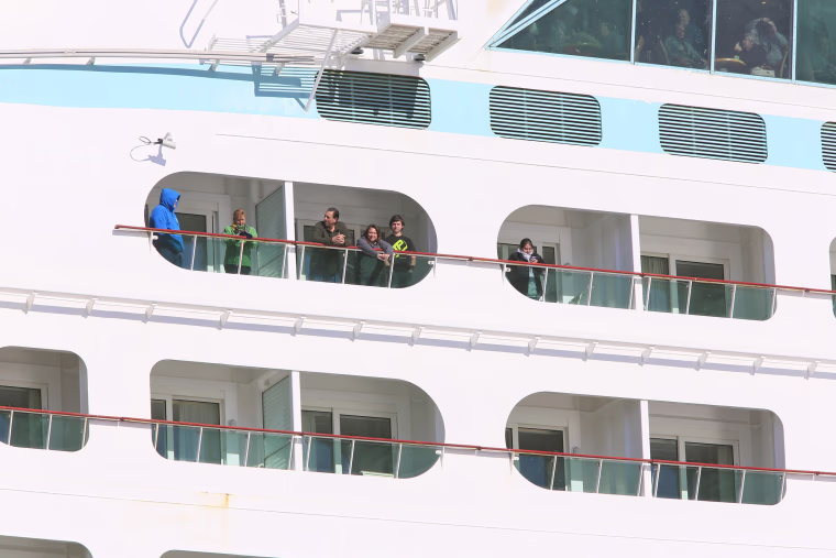 Passengers look out from the Explorers of the Sea as it returns to port.