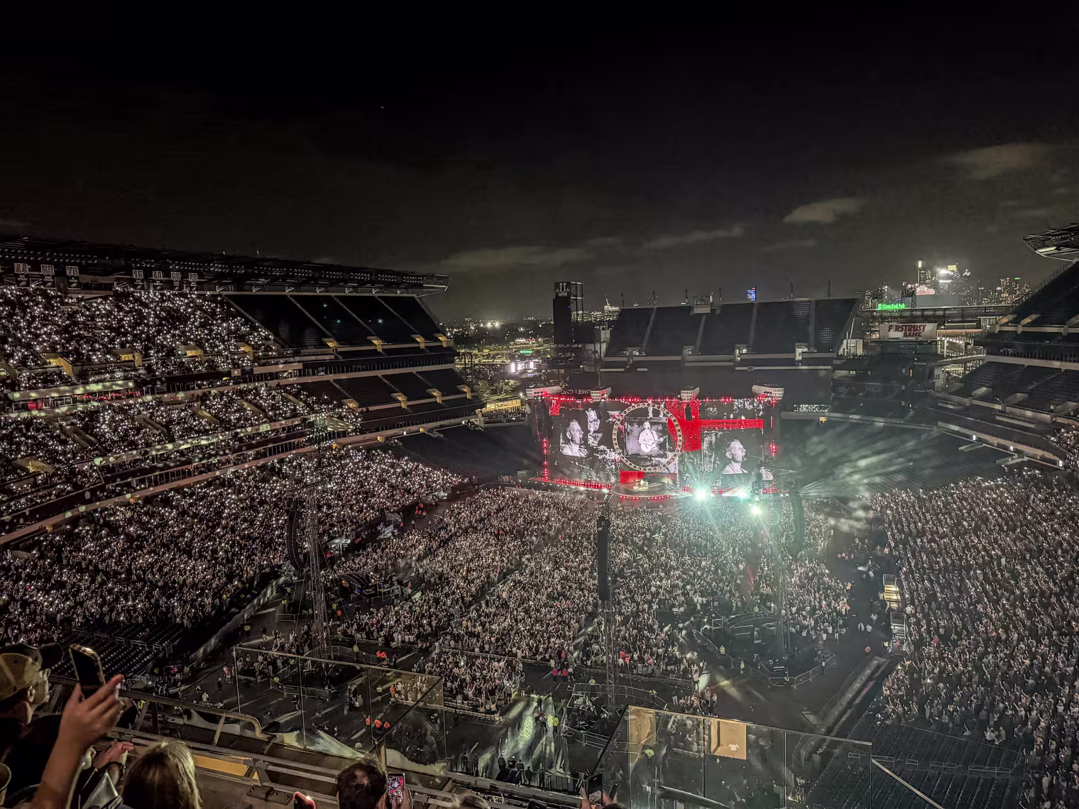 A wide shot of an outdoor stadium concert at night.