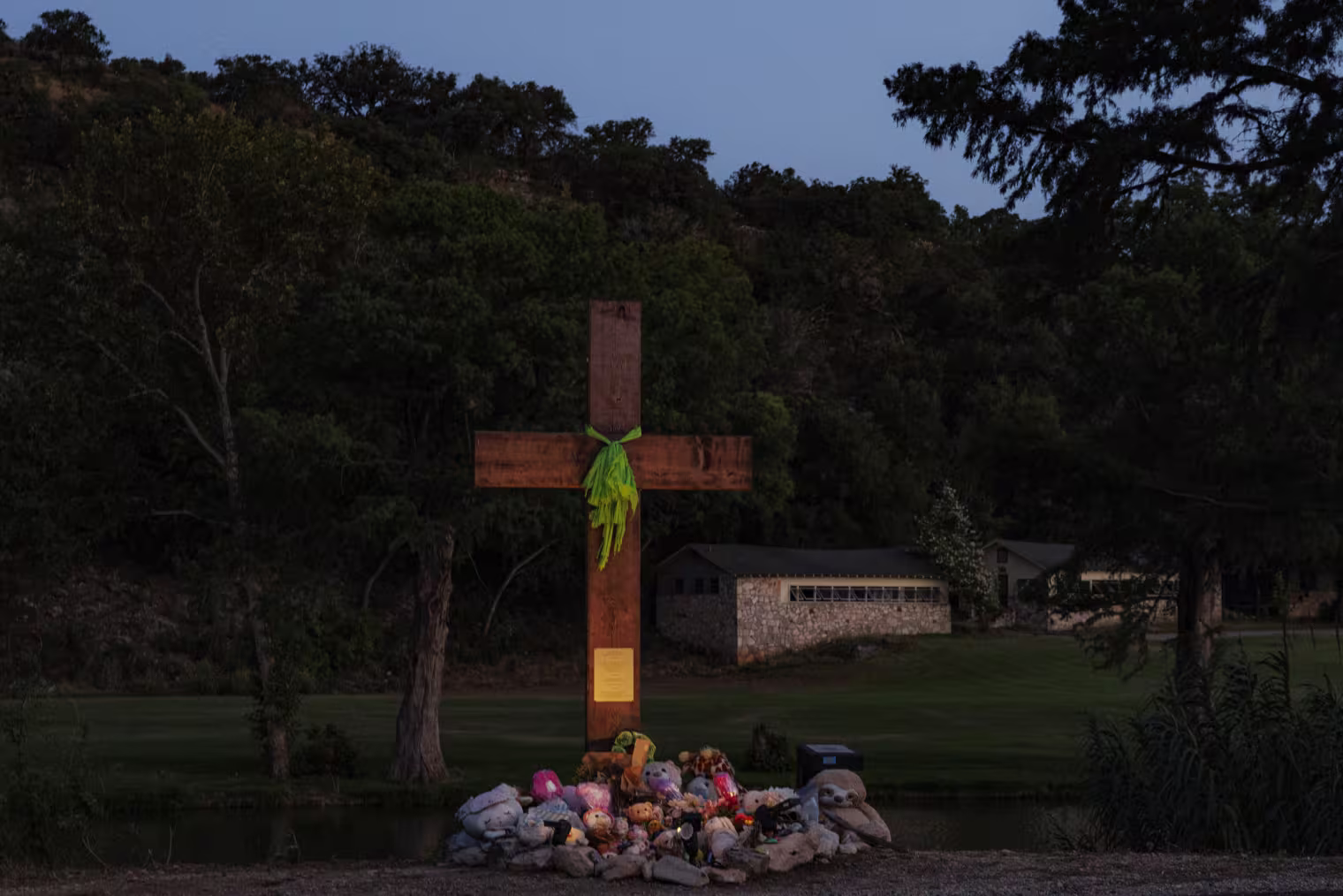 A wooden cross stands as a memorial over Camp Mystic along the Guadalupe River in Texas.
