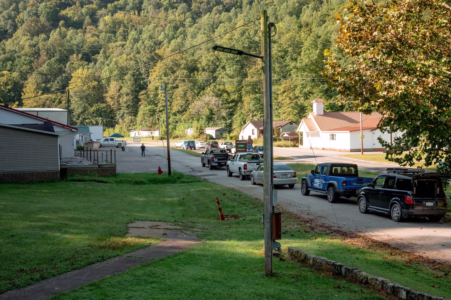 A line of cars wait to receive donated food during a weekly drive up food pantry at Dunlow Community Center
