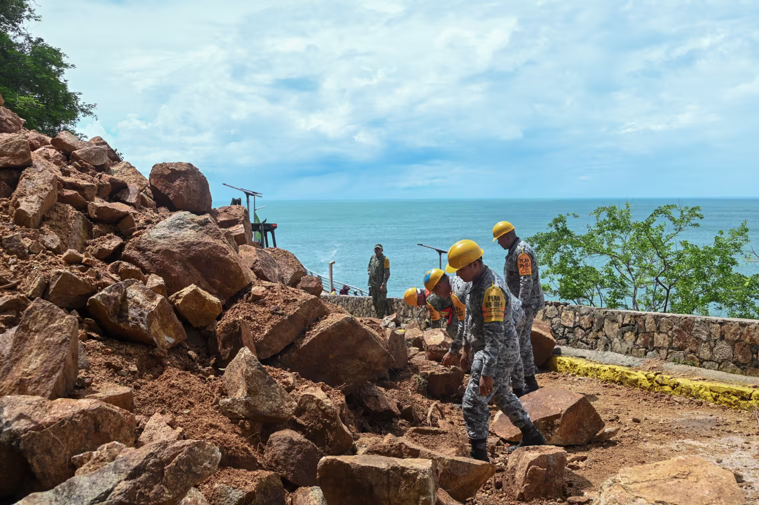 Members of the military and National Guard clear rubble outside