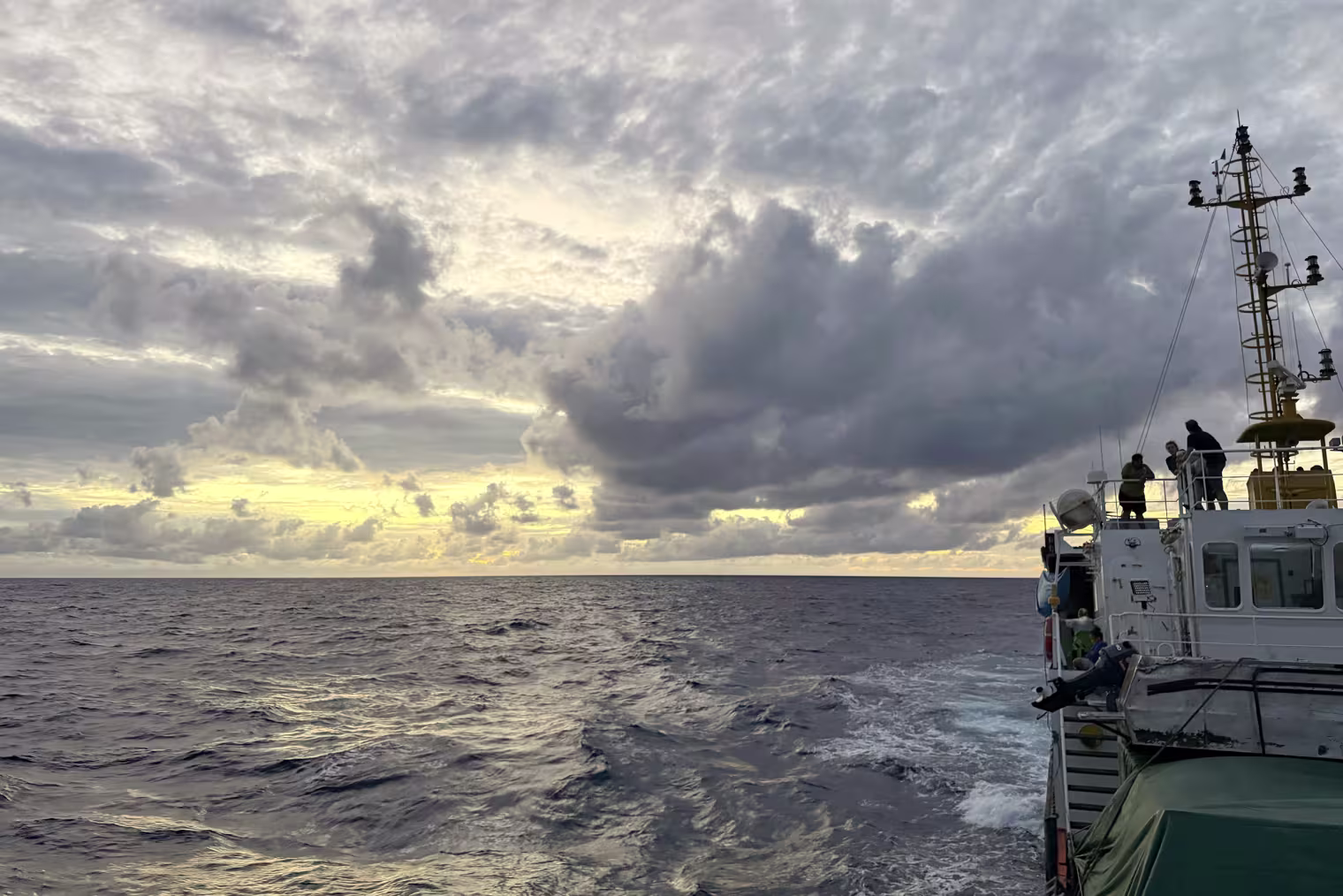 A wide landscape view of the open ocean with a ship in the side of the frame.