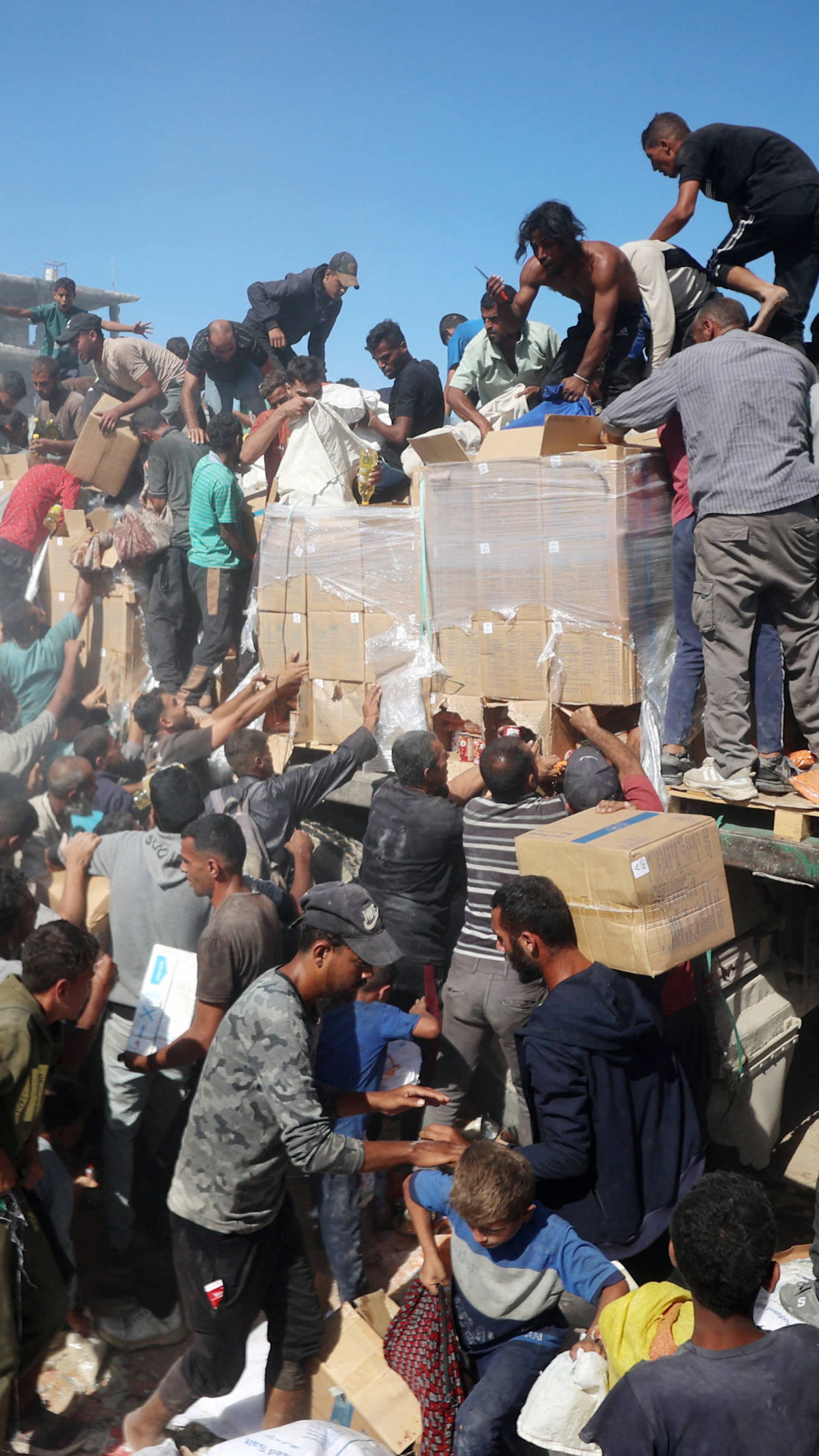 Palestinians crowd onto aid trucks moving through Gaza