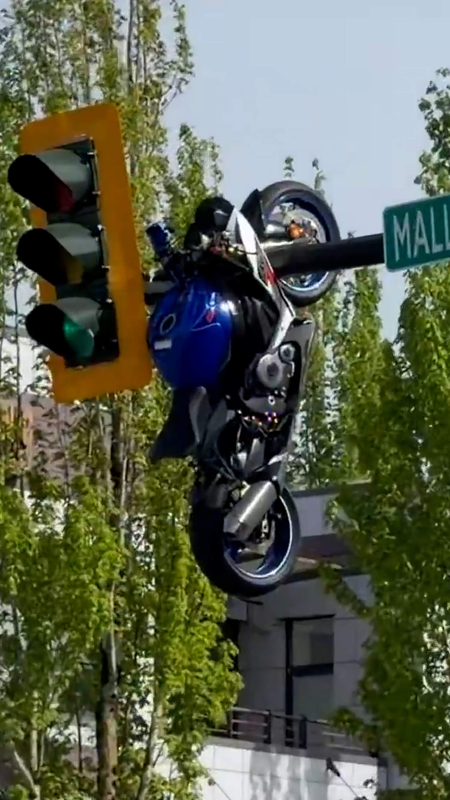 Motorcycle dangles from traffic light after collision
