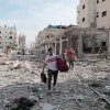 People walk through rubble and debris along a destroyed street while evacuating Gaza City