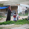 Children play next to a woman in the village of Khan al-Ahmar