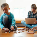 Boy playing toy blocks by mother using laptop at home