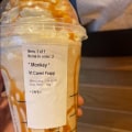 A large starbucks frappuchino with carmel swirls and a sticker with the name * Monkey * on it.
