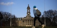 Image: A student walks in front of the Old Main building on the Penn State University campus on Nov. 11, 2011.