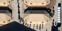 Image: Immigrant children are led by staff in single file between tents at a detention facility in Tornillo, Texas
