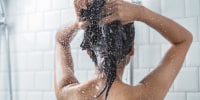 Woman washing her hair in the shower with shampoo