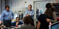 Editor Rick Hutzell, center, gives a speech to his staff at the Capital Gazette in Annapolis, Md., April 25, 2019.