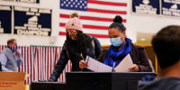 Two women, wearing protective masks cast their ballots at a polling station at Windham, N.H., on Nov. 3, 2020.