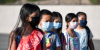 Masked students wait to be taken to their classrooms at Enrique S. Camarena Elementary School on July 21, 2021, in Chula Vista, Calif.