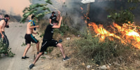 Image: People attempt to put out a fire in the mountainous Tizi Ouzou province, east of Algiers, Algeria