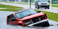 An abandoned vehicle is half submerged in a ditch next to a near flooded highway as the outer bands of Hurricane Ida arrive on Aug. 29, 2021, in Bay Saint Louis, Miss.